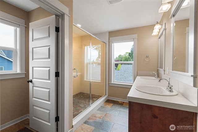 full bath featuring a sink, baseboards, a shower stall, and stone tile floors