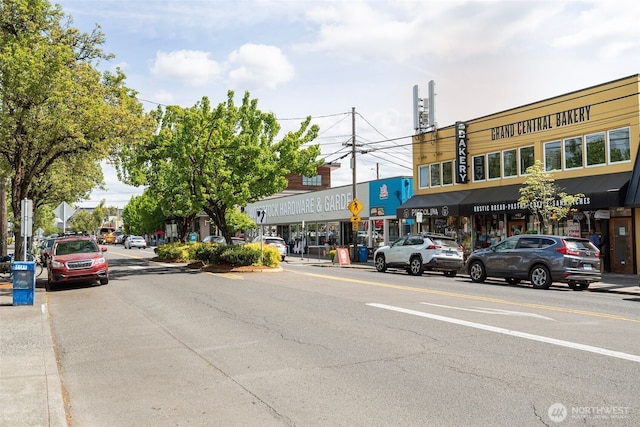 view of road featuring street lights, curbs, traffic signs, and sidewalks