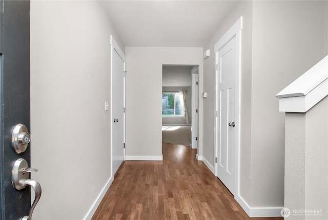 hallway featuring wood finished floors and baseboards