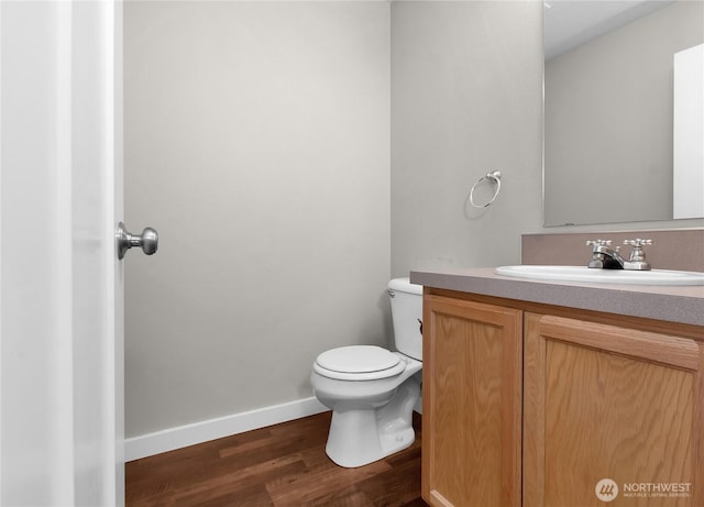 bathroom with toilet, wood finished floors, vanity, and baseboards