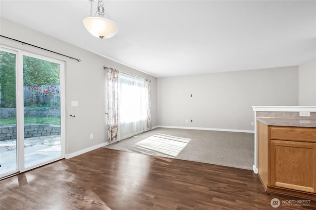 unfurnished living room featuring baseboards and dark wood-type flooring