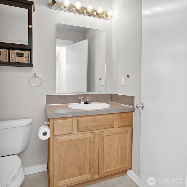 bathroom featuring toilet, baseboards, and vanity