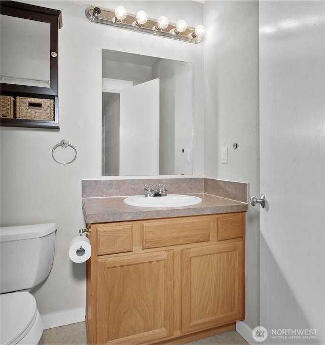 half bath with baseboards, toilet, and vanity