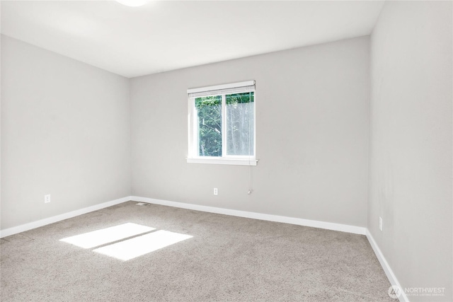 carpeted empty room featuring baseboards