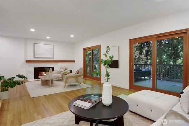 living area with a fireplace, light wood finished floors, recessed lighting, and baseboards