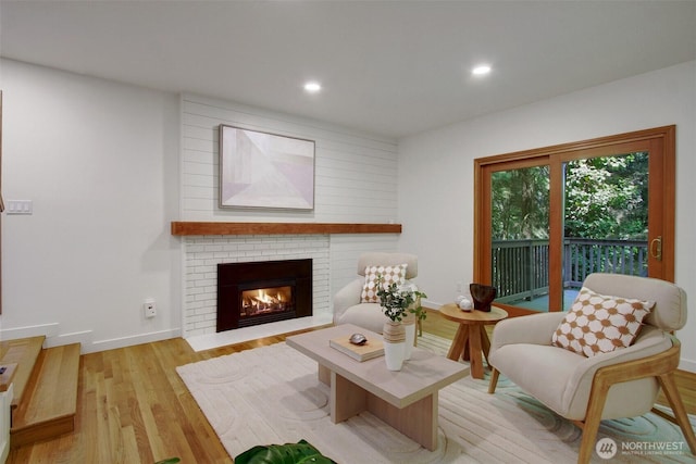 living area featuring light wood-style floors, a brick fireplace, recessed lighting, and baseboards