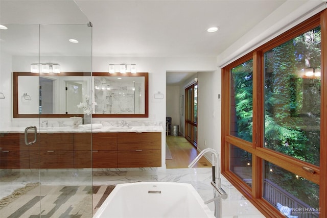 bathroom featuring a soaking tub, double vanity, recessed lighting, and an enclosed shower