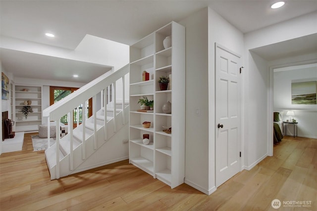 staircase with wood finished floors, recessed lighting, and baseboards