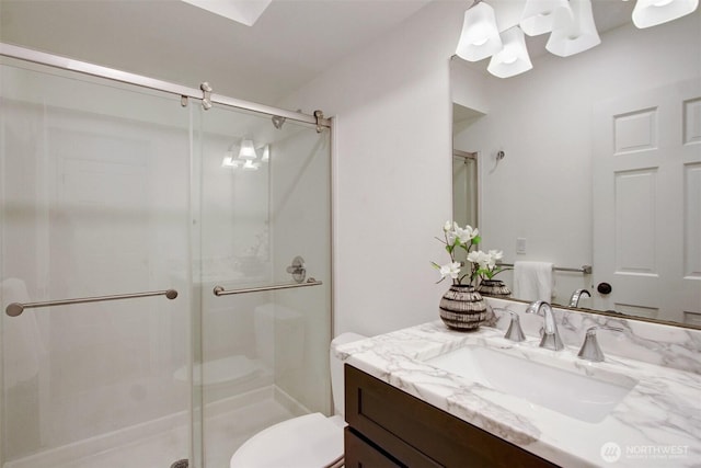 bathroom featuring a shower stall, toilet, and vanity
