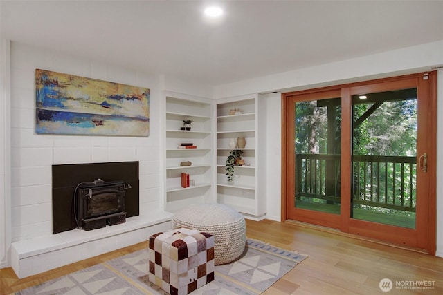 living area with a wood stove, wood finished floors, and built in features