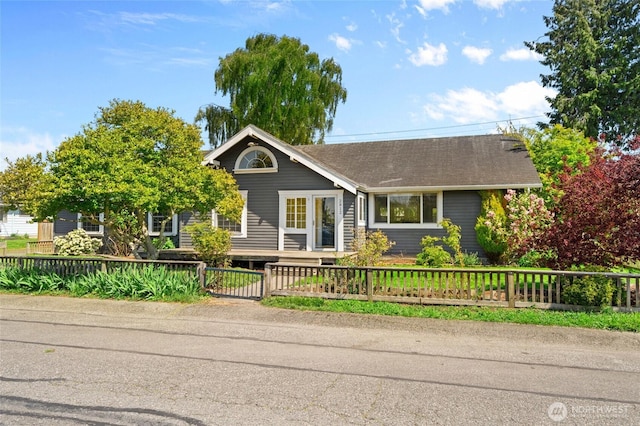 single story home with a fenced front yard and roof with shingles
