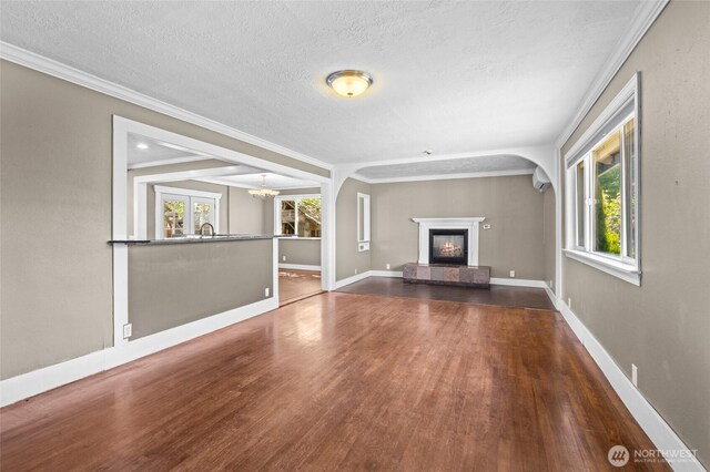unfurnished living room with a textured ceiling, plenty of natural light, wood finished floors, and a tiled fireplace