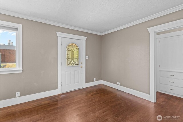 foyer entrance featuring a textured ceiling, baseboards, wood finished floors, and a wealth of natural light