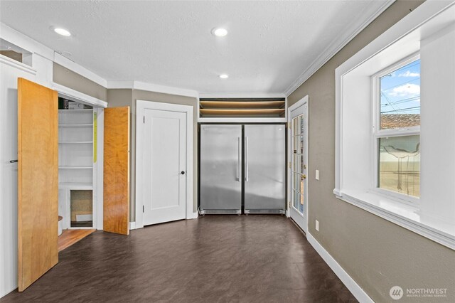unfurnished bedroom featuring crown molding, freestanding refrigerator, baseboards, recessed lighting, and finished concrete floors