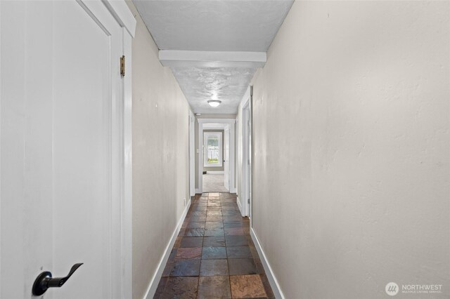 hall featuring baseboards and stone tile floors