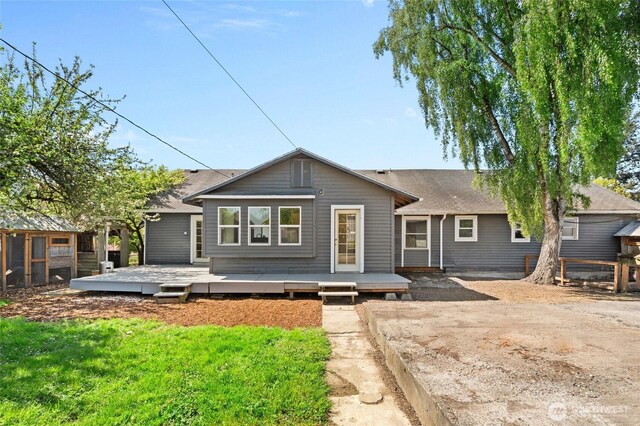 rear view of house featuring a shingled roof, a wooden deck, and fence