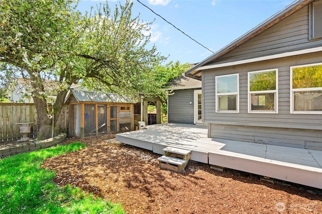 rear view of house with exterior structure, fence, an outbuilding, and a deck