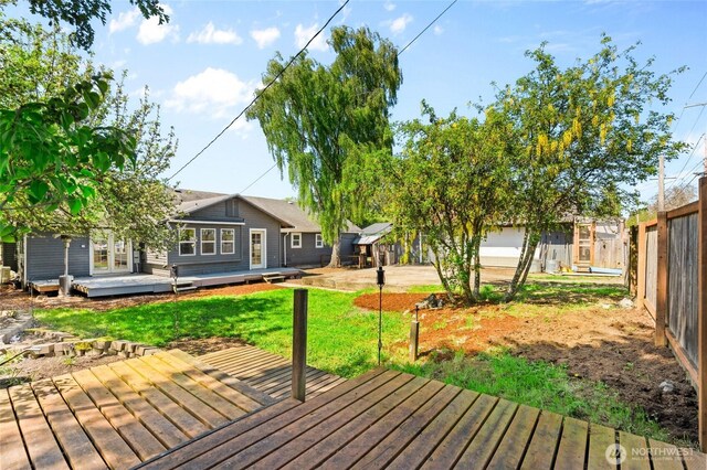 wooden terrace featuring a lawn and fence