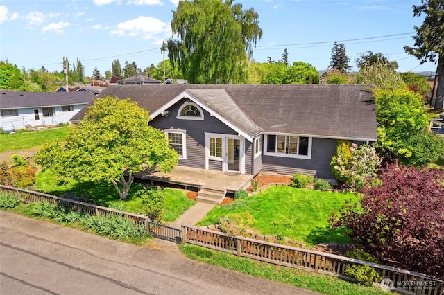 single story home featuring roof with shingles, a wooden deck, and a fenced front yard