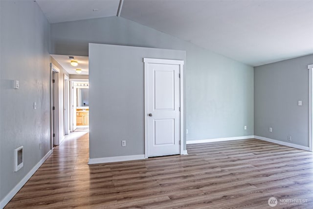 unfurnished living room featuring baseboards, visible vents, wood finished floors, and vaulted ceiling