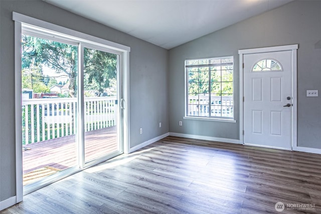 foyer with baseboards, vaulted ceiling, a healthy amount of sunlight, and wood finished floors