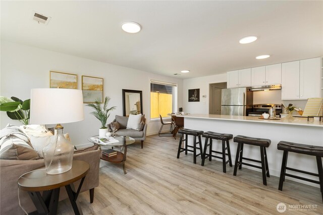 living area featuring recessed lighting, visible vents, and light wood finished floors