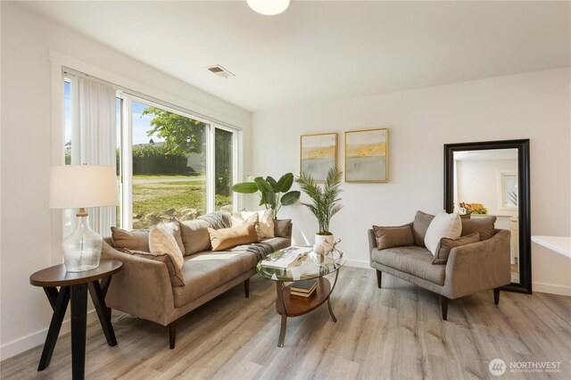 living area featuring baseboards, visible vents, and light wood-style flooring