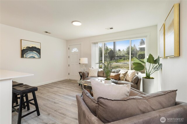 living room with visible vents, light wood finished floors, and baseboards