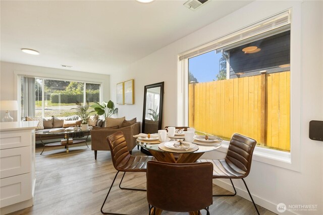 dining area with light wood-style flooring and visible vents