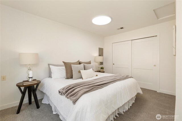 carpeted bedroom with a closet, baseboards, attic access, and visible vents