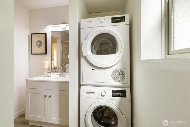laundry room featuring laundry area, stacked washing maching and dryer, and a sink