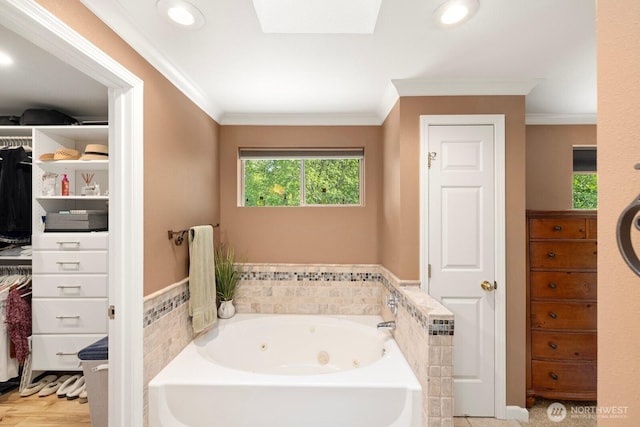 full bath featuring crown molding, a whirlpool tub, a skylight, and tile walls