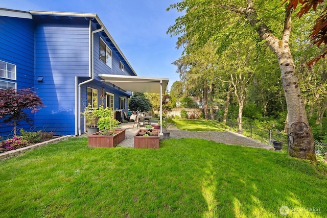view of yard featuring a patio, fence, and a garden