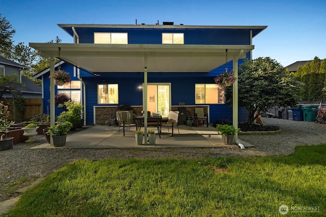 back of property featuring fence, a patio, and a lawn