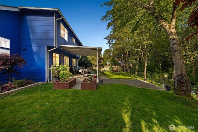view of yard with a patio area, fence, and a vegetable garden