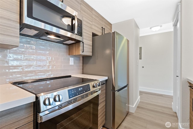 kitchen with range with electric cooktop, tasteful backsplash, modern cabinets, light countertops, and stainless steel microwave