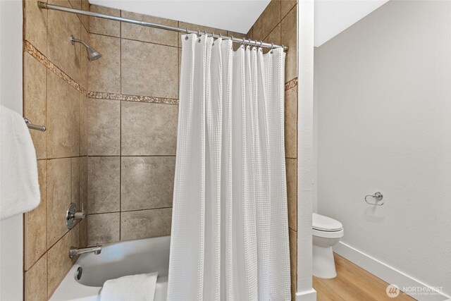 full bath featuring baseboards, toilet, wood finished floors, and shower / bath combination with curtain