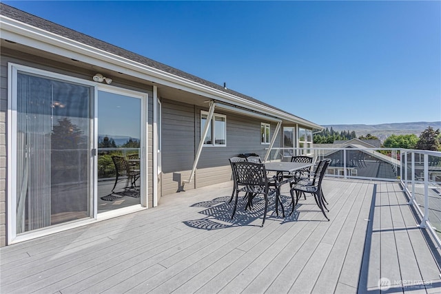 wooden terrace with outdoor dining space and a mountain view