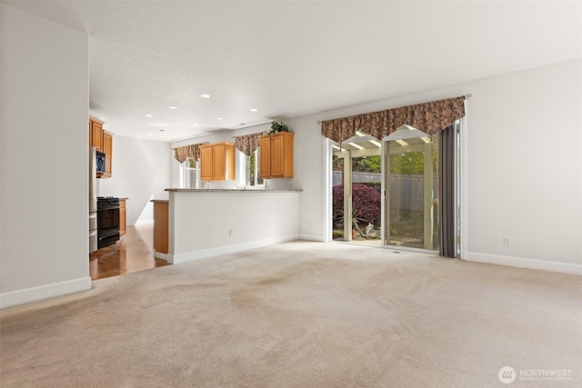 unfurnished living room with baseboards, plenty of natural light, recessed lighting, and light colored carpet