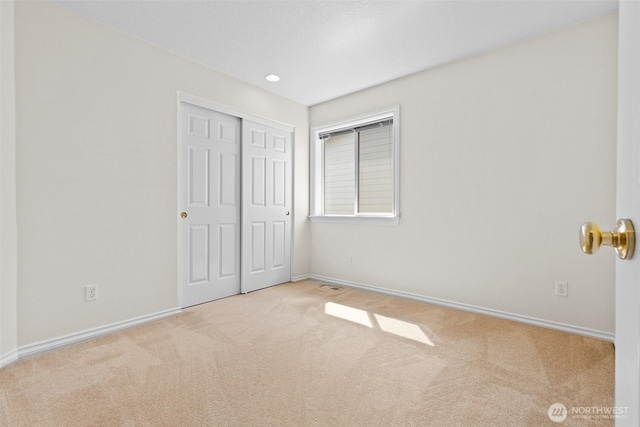 unfurnished bedroom with baseboards, carpet flooring, and a closet