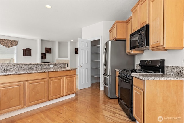 kitchen featuring light brown cabinetry, light stone counters, recessed lighting, light wood-type flooring, and black appliances