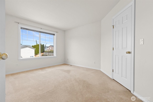 spare room featuring baseboards and light carpet