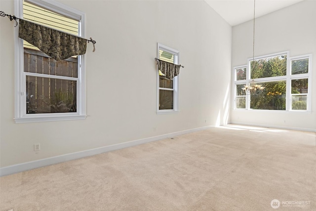 carpeted empty room featuring baseboards and a high ceiling