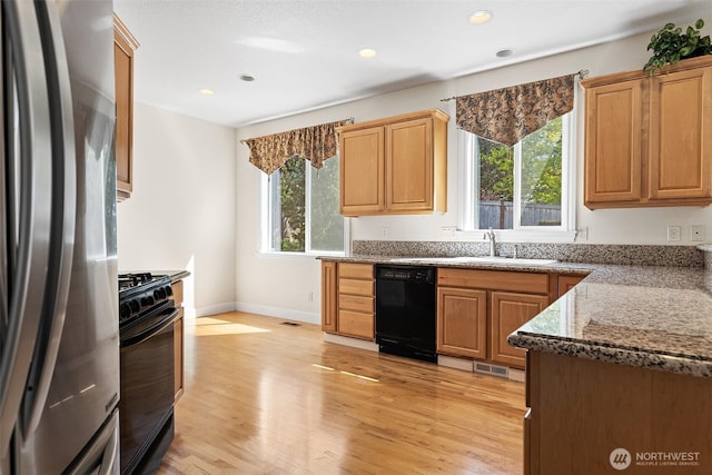 kitchen with recessed lighting, a sink, light wood finished floors, and black appliances