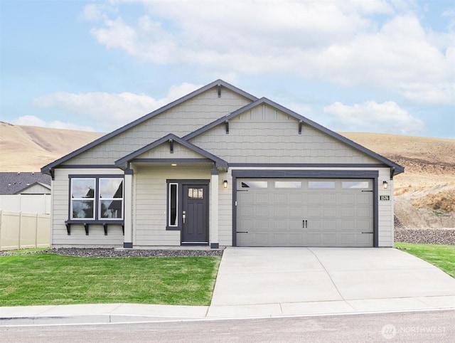 view of front facade featuring concrete driveway, an attached garage, fence, and a front lawn