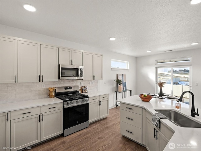 1349 Bill Ave, Walla Walla, WA 99362 - kitchen with stainless steel appliances, a sink, decorative backsplash, dark wood-type flooring, and recessed lighting