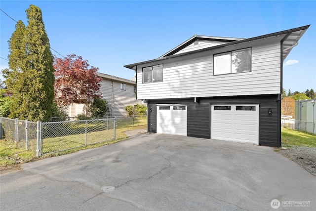 view of side of home featuring a yard, fence, aphalt driveway, and a garage