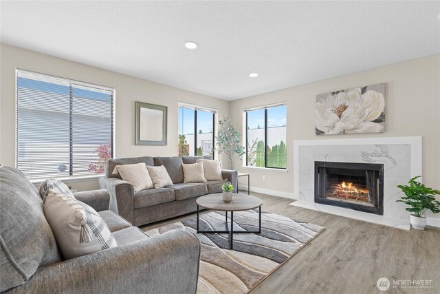living room featuring a premium fireplace, baseboards, recessed lighting, and wood finished floors