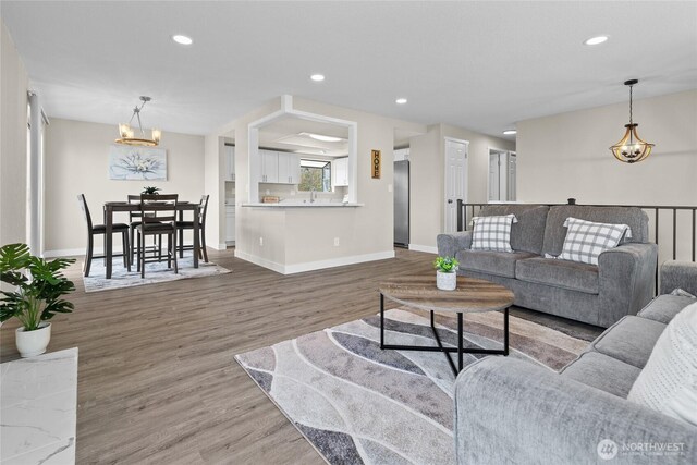 living area with recessed lighting, baseboards, a chandelier, and wood finished floors