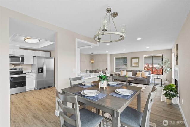 dining area featuring recessed lighting, baseboards, an inviting chandelier, and light wood-style floors